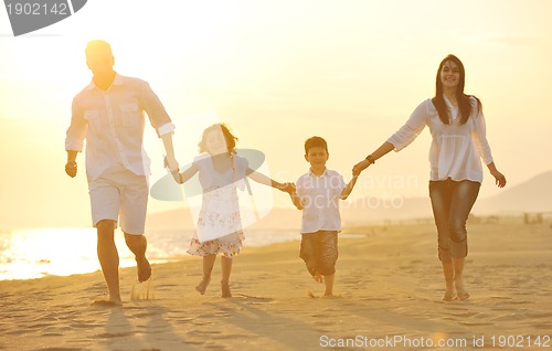 Image of happy young family have fun on beach at sunset