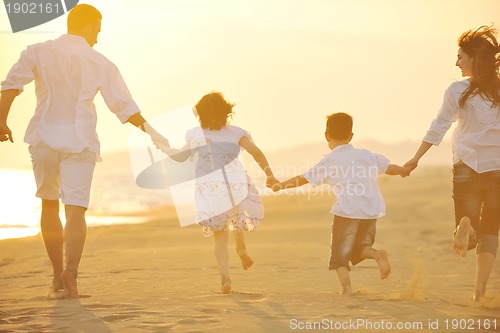 Image of happy young family have fun on beach at sunset