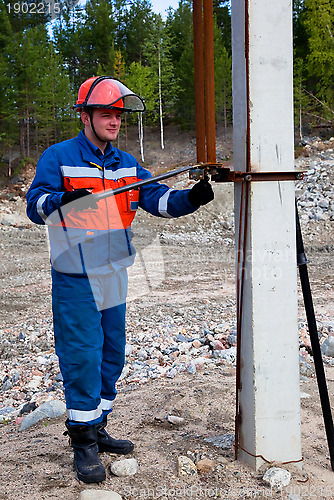 Image of Electrician in blue overalls makes switching