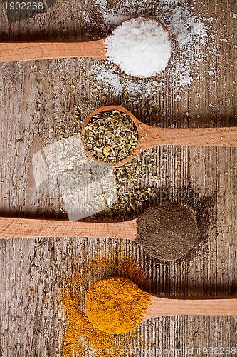 Image of curry, pepper, oregano and cooking salt in wooden spoons