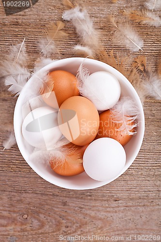Image of eggs and feathers on wooden table