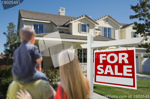 Image of Family Looking at New Home with For Sale Sign 