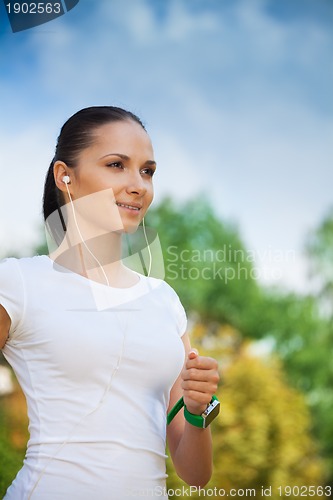 Image of young positive jogger in park