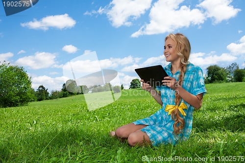 Image of student sitting on grass browsing