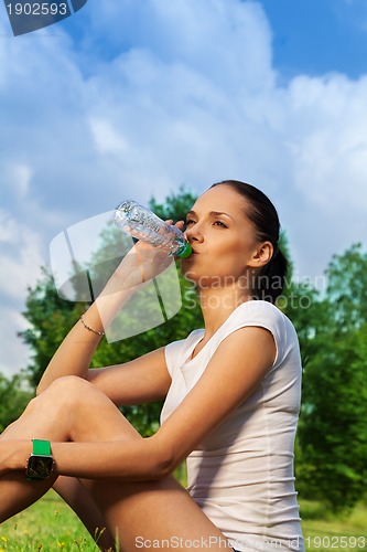 Image of beautiful jogger resting and drinking water