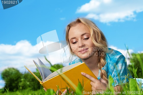 Image of pretty girl  reading book outdoors