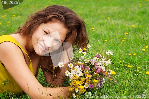 Image of beautiful girl laying on grass with bouquet