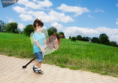 Image of kid playing with horse stick