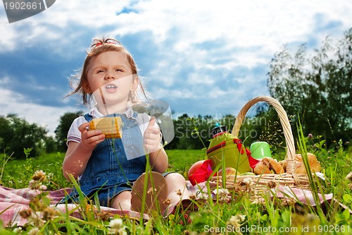 Image of Thoughtful girl eating corn on picnic