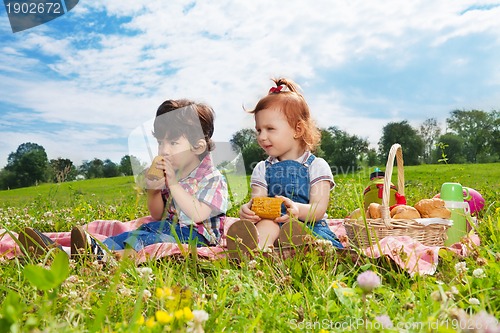 Image of two cute kids eating lunch on picnic