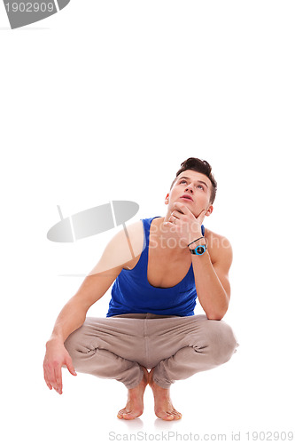 Image of pensive man squatting down in bare feet 