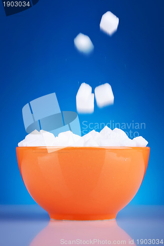 Image of sugar cubes falling in an orange bowl 