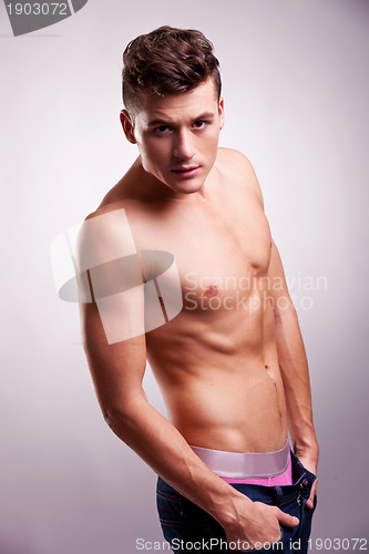 Image of slim and muscular man posing on gray
