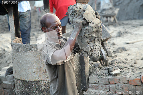 Image of Brick field. Laborers are carrying deposited soil for making raw brick. in Sarberia, West Bengal, India.