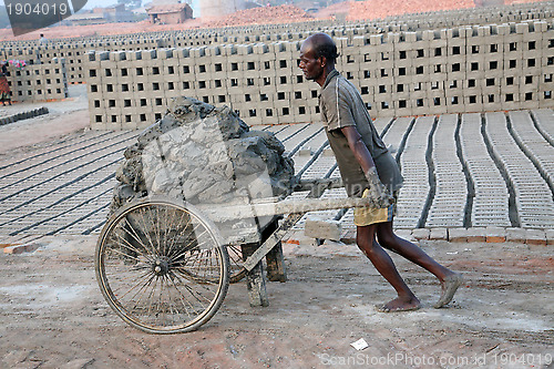 Image of Brick field. Laborers are carrying deposited soil for making raw brick. in Sarberia, West Bengal, India.