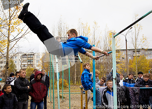 Image of Young guys compete on the horizontal  bar