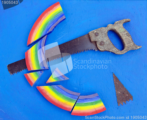 Image of Concept rainbow cut with hand saw blue background 