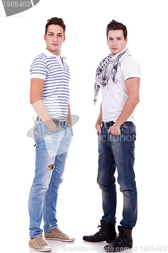 Image of two  friends standing  with their hands in pockets