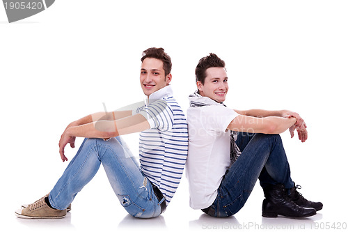 Image of two young casual men sitting back to back 