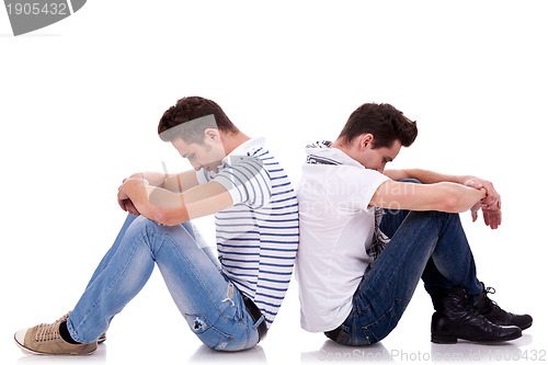 Image of two sad men sitting back to back