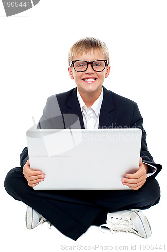 Image of Cheerful young kid sitting on the floor with a laptop