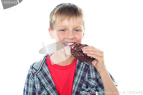 Image of Fashionable young boy eating chocolate cookie