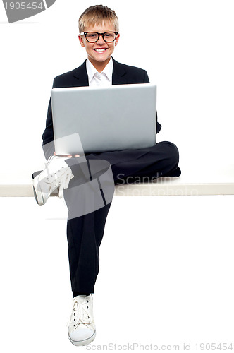 Image of Smartly dressed young kid working on a laptop