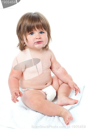 Image of Cute baby girl sitting up wearing a diaper