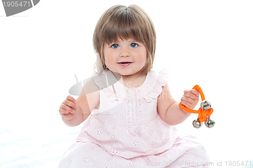Image of Healthy baby girl sitting on floor playing with rattle