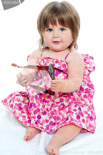 Image of Baby girl sitting with shades in her hand