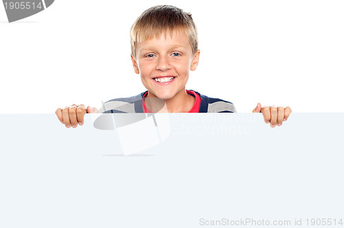Image of Stylish boy standing behind big blank banner ad