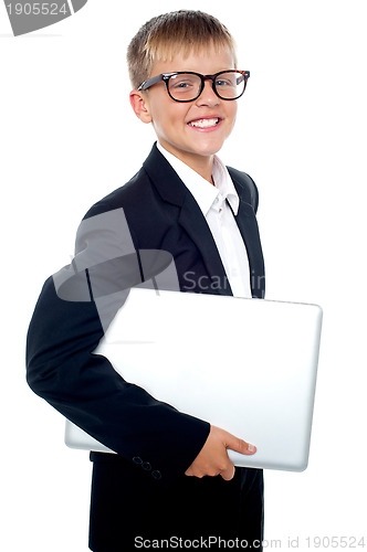 Image of Bespectacled young boy carrying a laptop