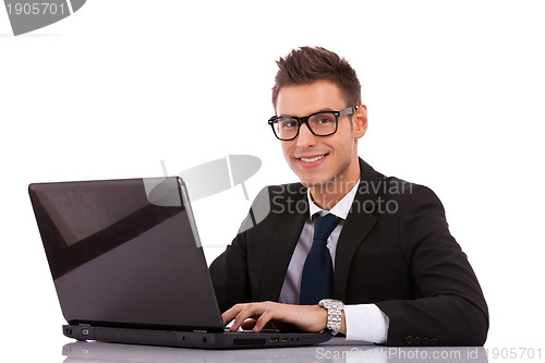 Image of business man wearing glasses  using a laptop 