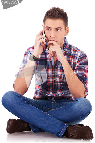 Image of pensive man sitting and talking on the phone