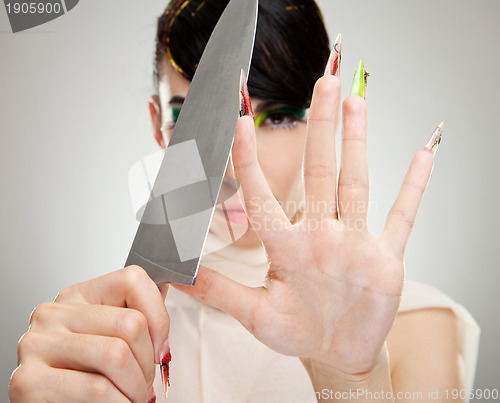 Image of woman sharpening her nails with knife