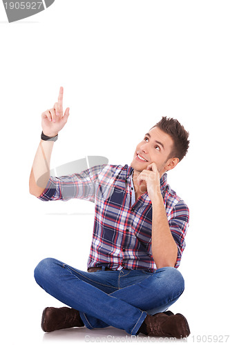 Image of seated young casual man pointing at something up