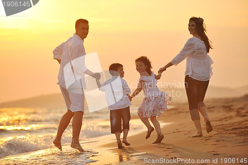 Image of happy young family have fun on beach at sunset
