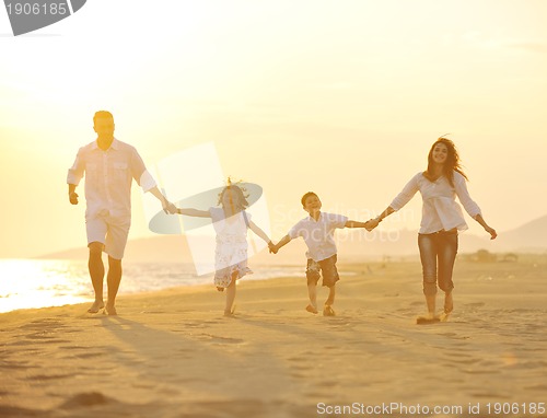 Image of happy young family have fun on beach at sunset