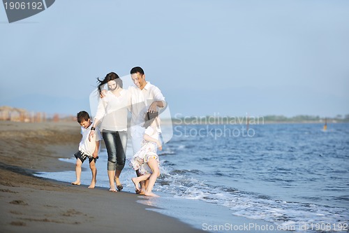 Image of happy young family have fun on beach at sunset