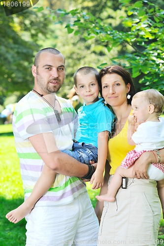 Image of happy young couple with their children have fun at park
