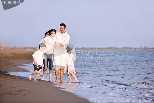 Image of happy young family have fun on beach at sunset