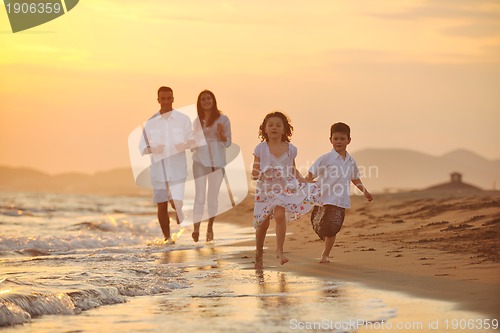 Image of happy young family have fun on beach at sunset
