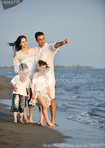 Image of happy young family have fun on beach at sunset
