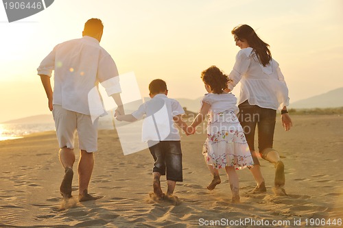 Image of happy young family have fun on beach at sunset