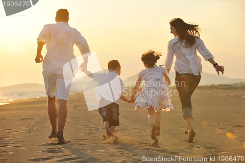 Image of happy young family have fun on beach at sunset