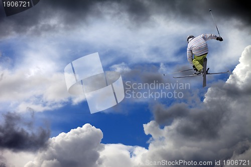 Image of Freestyle ski jumper with crossed skis against cloudy sky