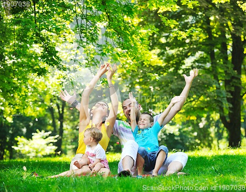 Image of happy young couple with their children have fun at park