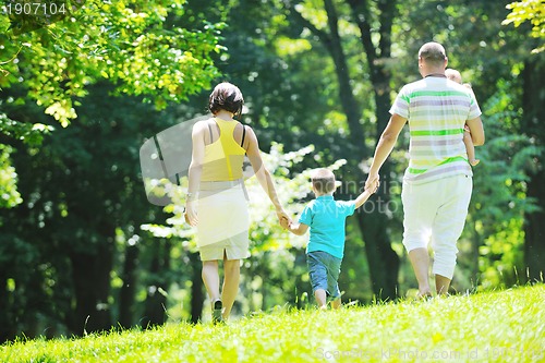 Image of happy young couple with their children have fun at park