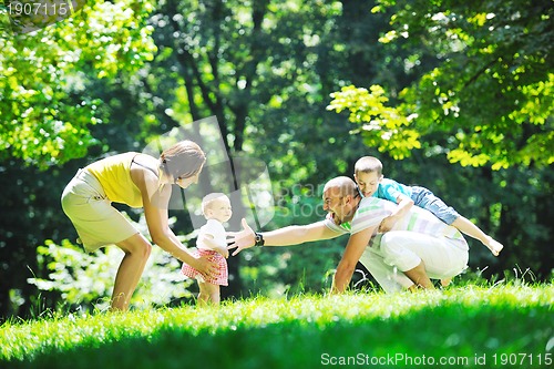 Image of happy young couple with their children have fun at park