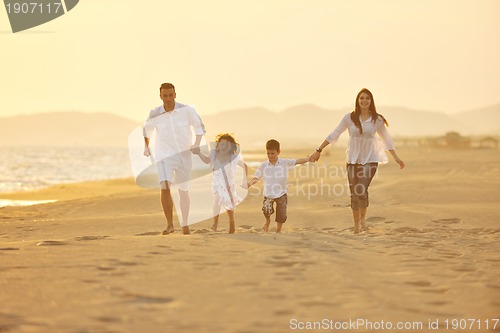 Image of happy young family have fun on beach at sunset